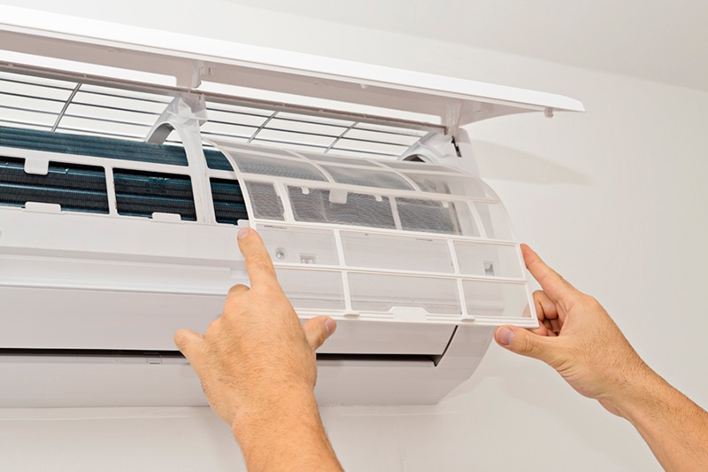 Hands opening the panel of a ductless system | What Maintenance Is Needed for a Ductless System? | San Marcos, TX